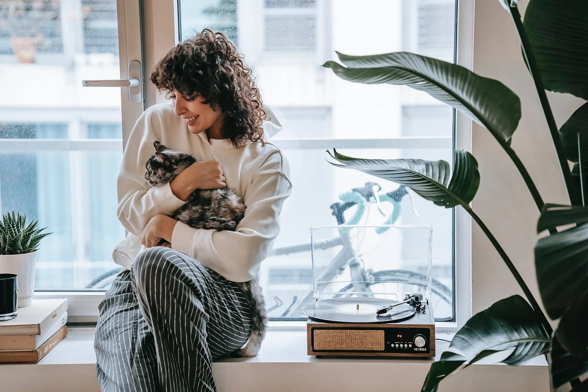 women sitting next to a cat and a plant